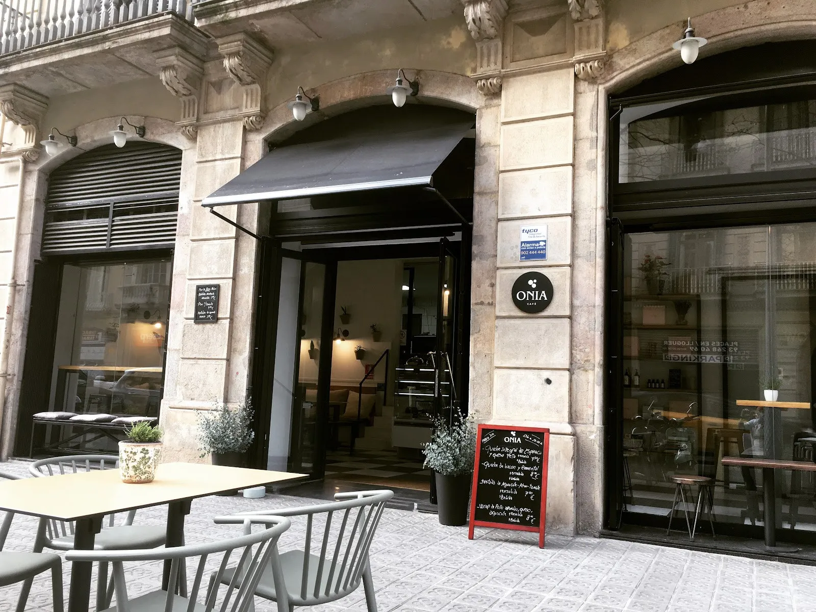 La fachada de Onia Cafè, con su toldo negro y mesas fuera