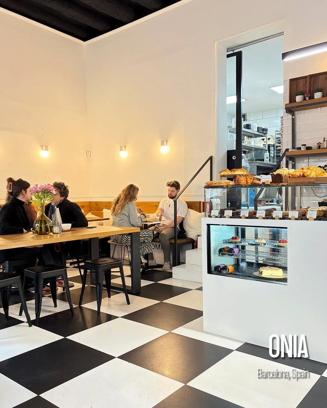 Interior de Onia Cafè, con suelo de baldosas blancas y negras, la barra y la vitrina