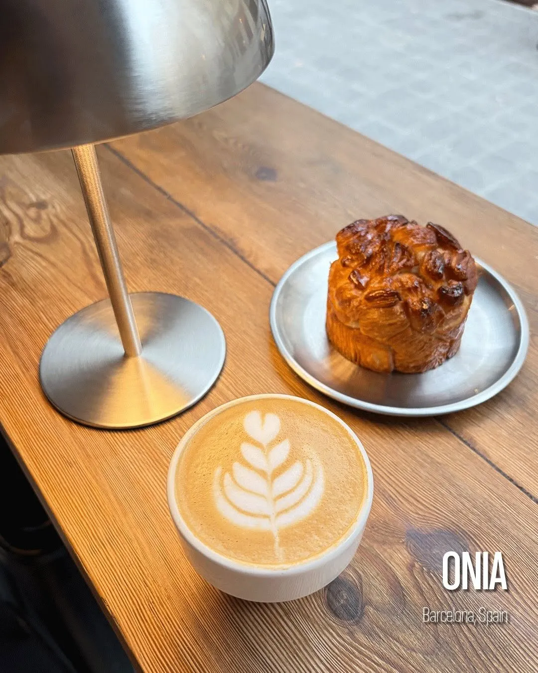 Un café con leche con arte latte y una pieza de bollería