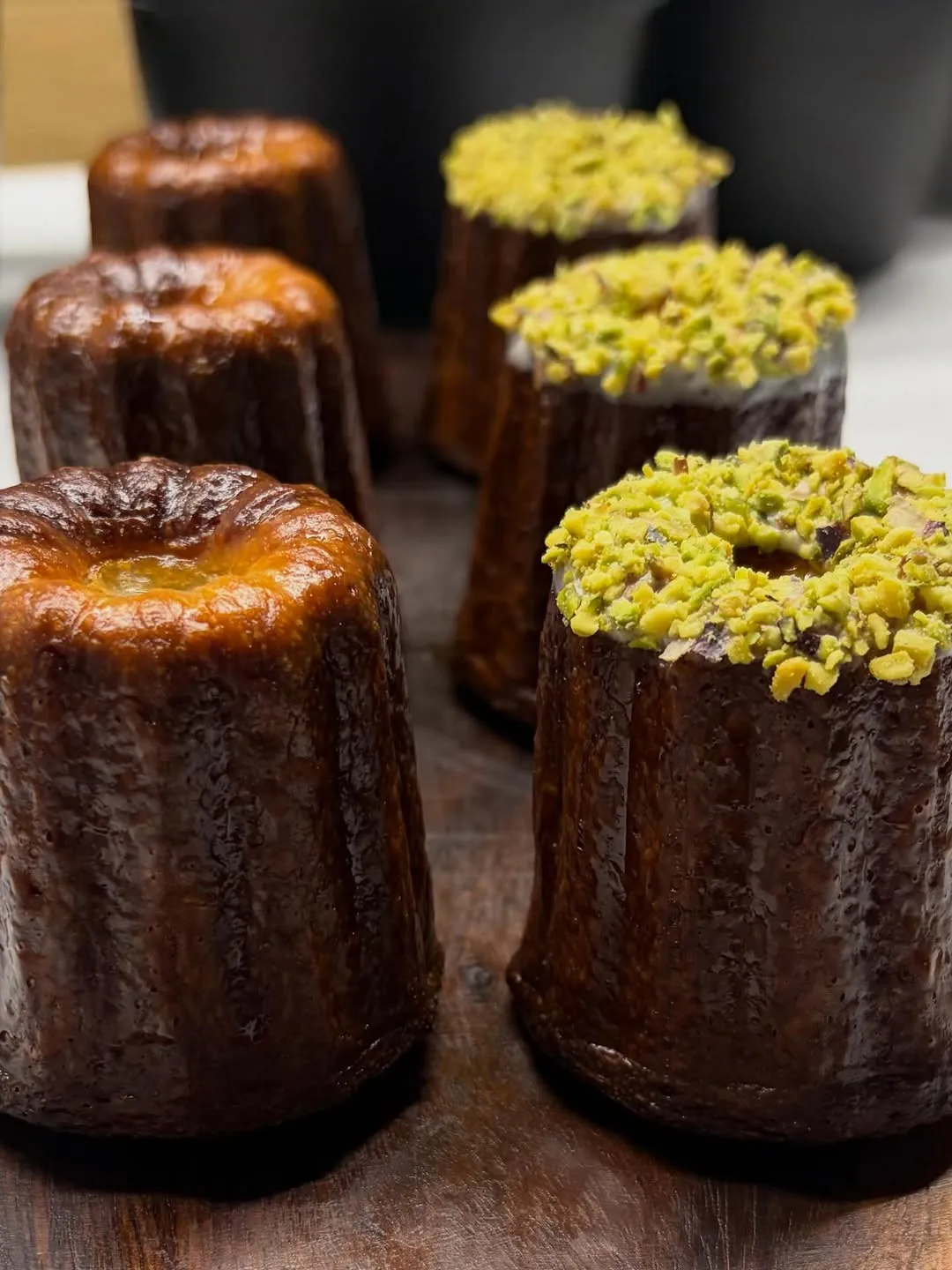 Canelés, algunos cubiertos de pistacho